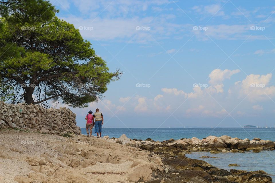 View of a lonely couple walking by the sea