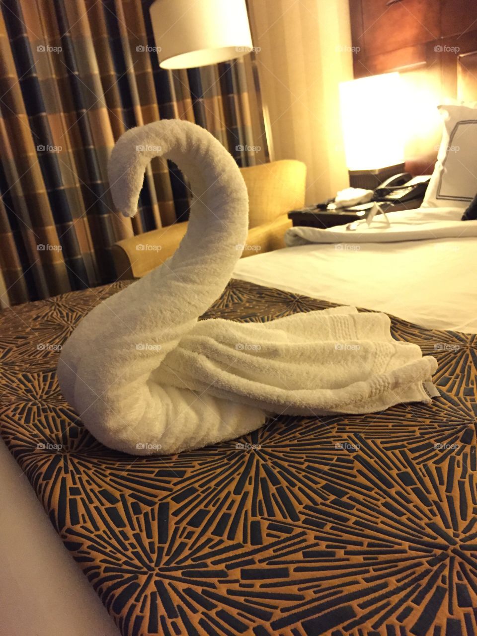Hotel towel folded into a swan on a bed.
