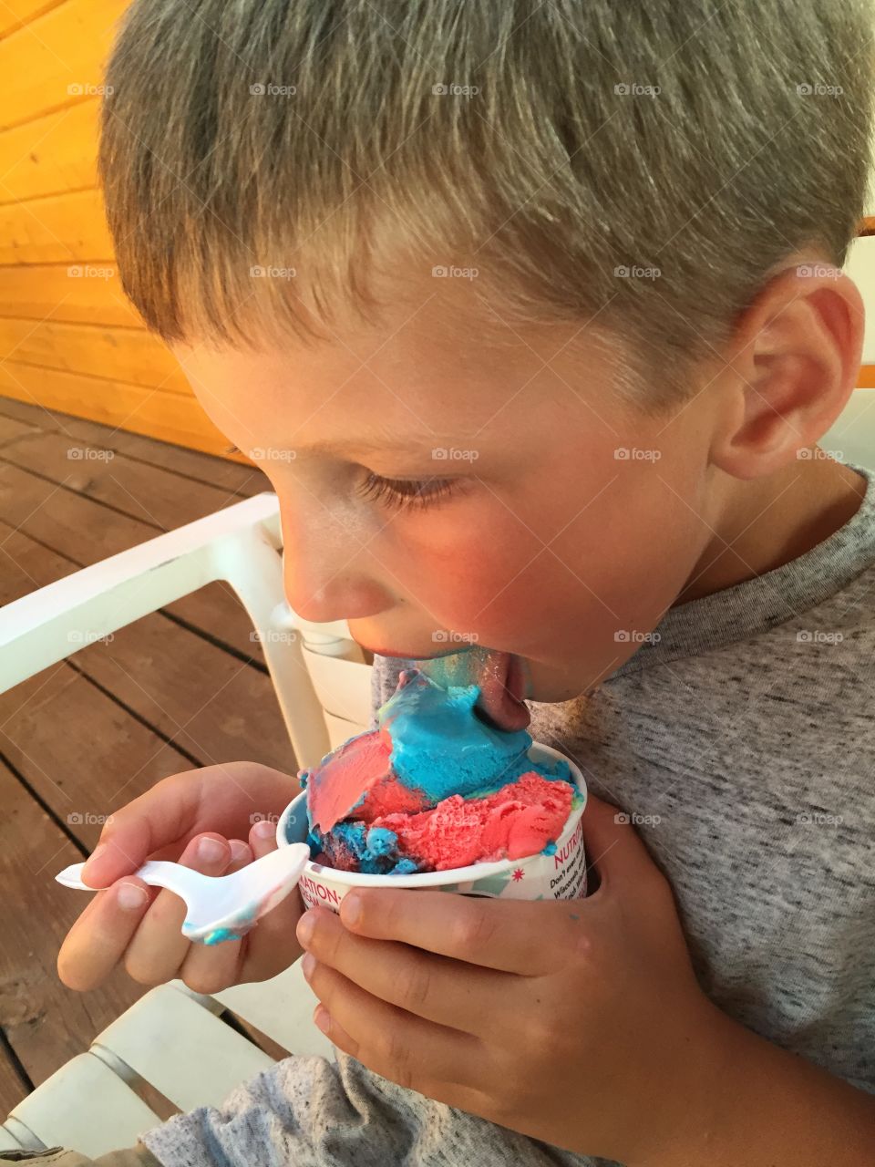 A young boy enjoys “Superman” flavored ice cream on a hot summer afternoon.