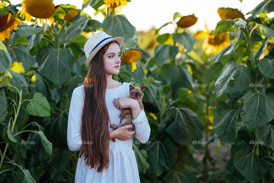 A girl in straw hat holds her cat. That special bond between owner and pet