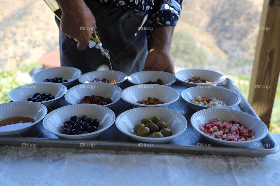 Hand pouring olive oil on the food in small plates