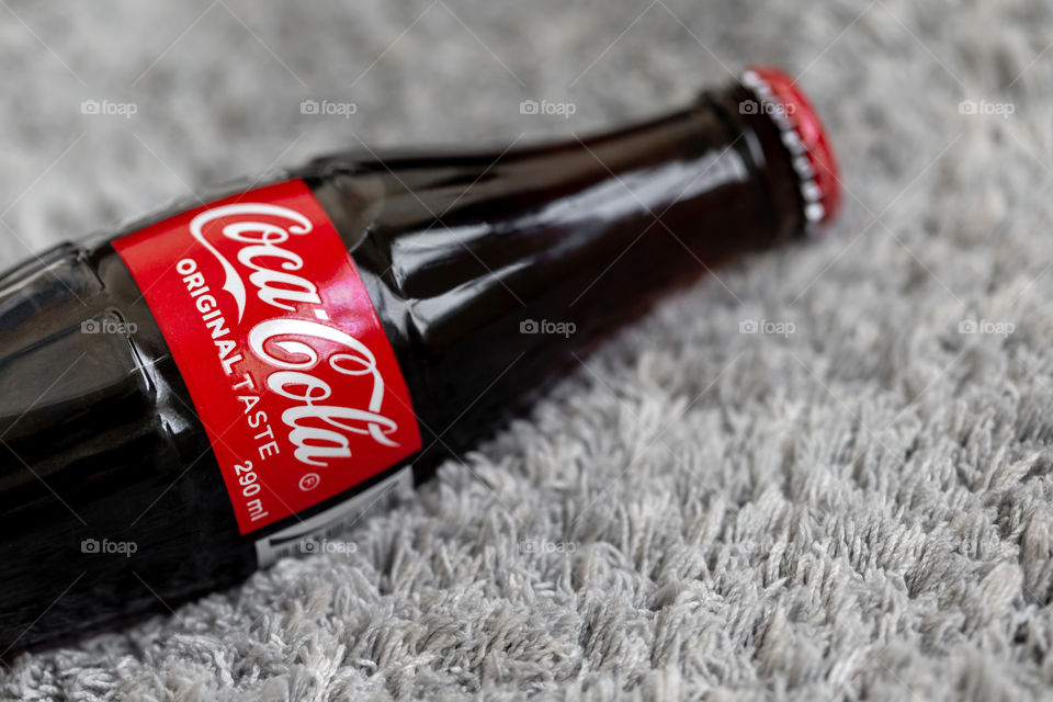 Coca-cola glass bottle on grey plush background, closeup