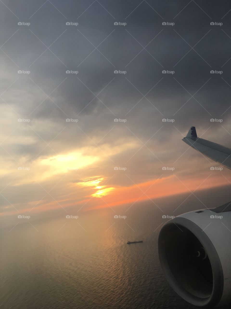 Sunrise over the ocean. Plane passes a boat 