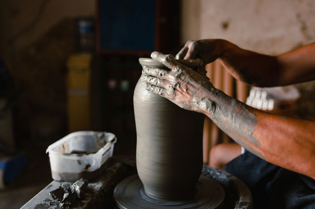 Close-up on hands of craftsman while working clay pot in his workshop