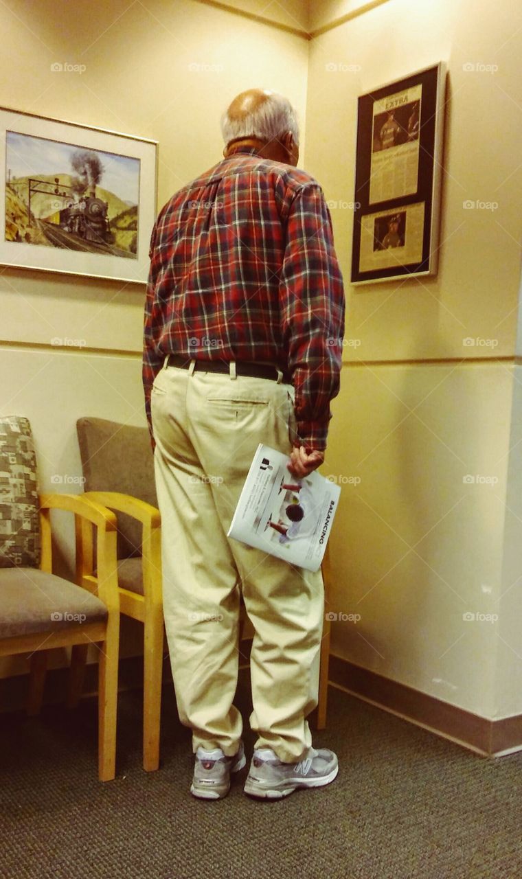 This man was reading a plaque while waiting for his turn with the eye doctor.