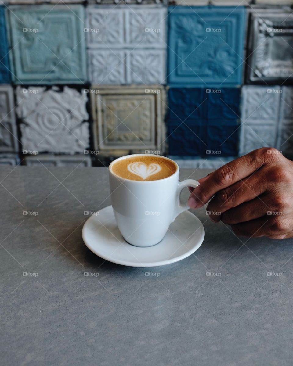 Person holding cup of coffee with latte art
