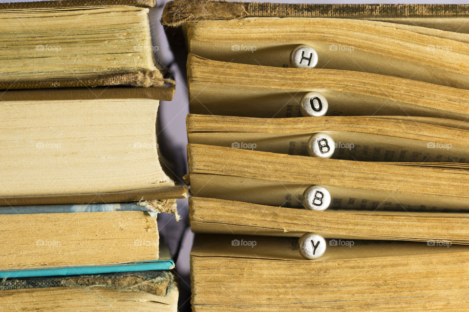 A stack of books with the inscription on the silver beads Hobby. my hobby is reading of books.  a books open new worlds to me and make me happy.  I think it's the best hobby in the world!