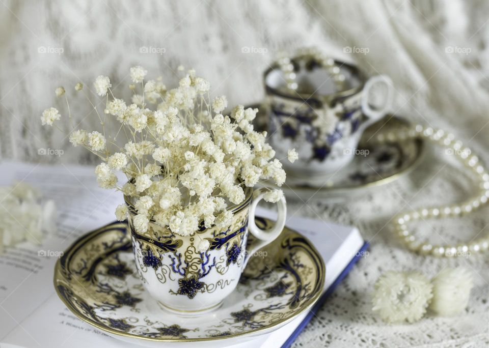 Victorian teacups with dried flowers, book and pearls