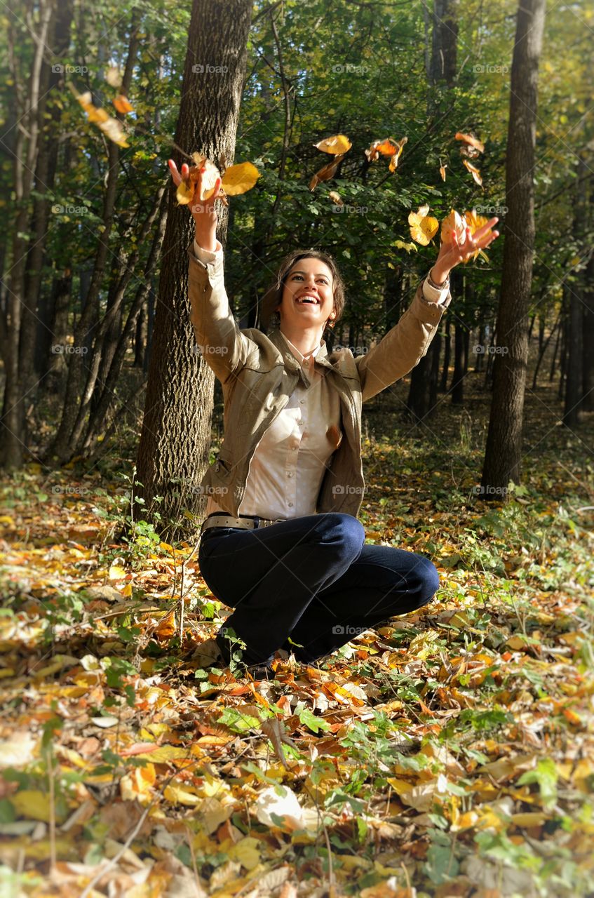 Young woman throwing autumn leaves