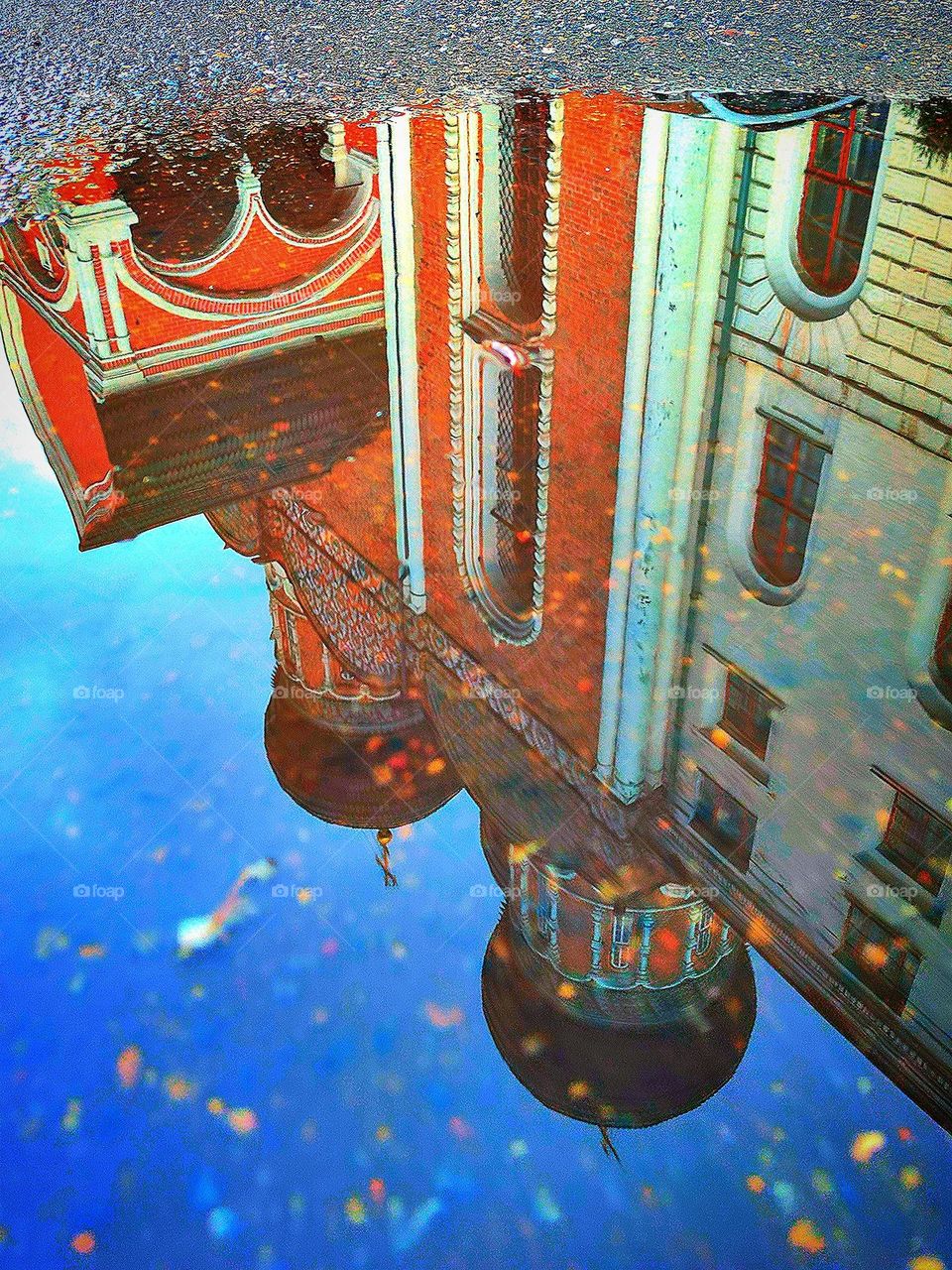 View from the asphalt.  A puddle on the pavement reflects the temple and the blue sky