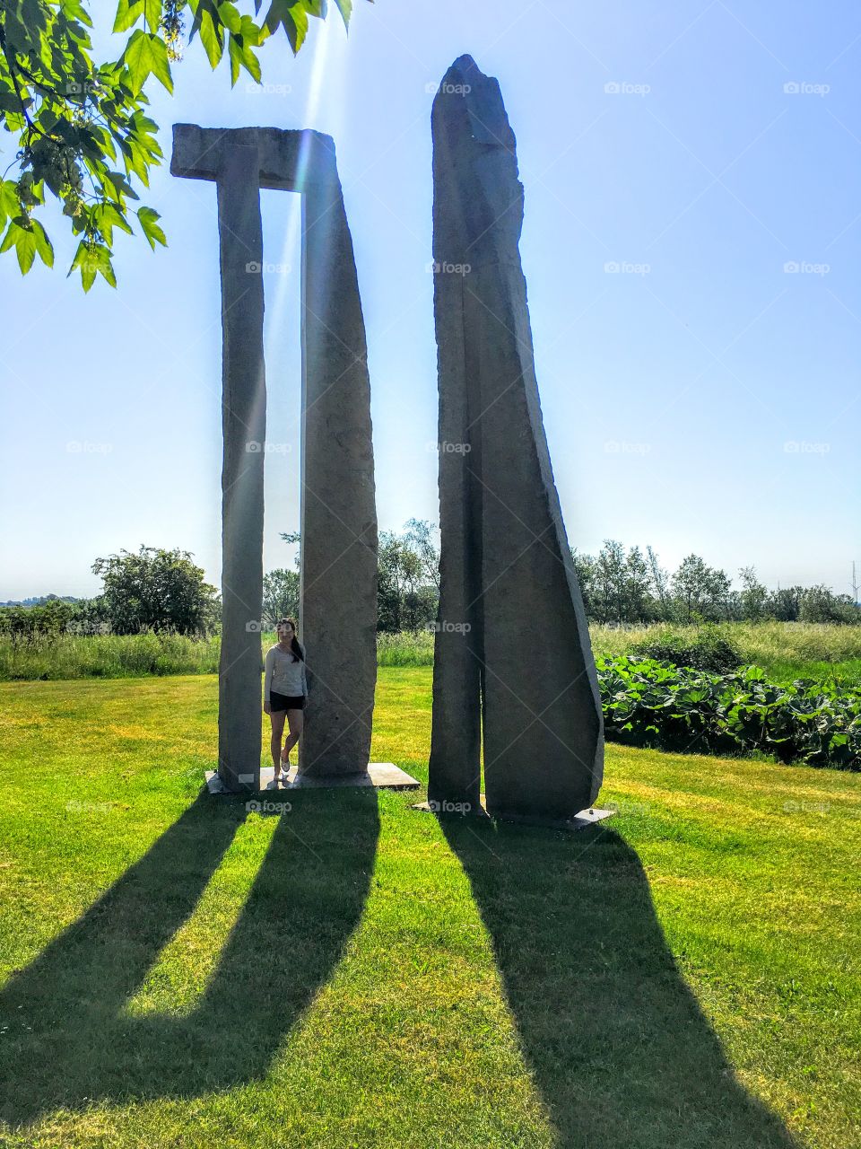 Woman leaning against stone sculpture on grass