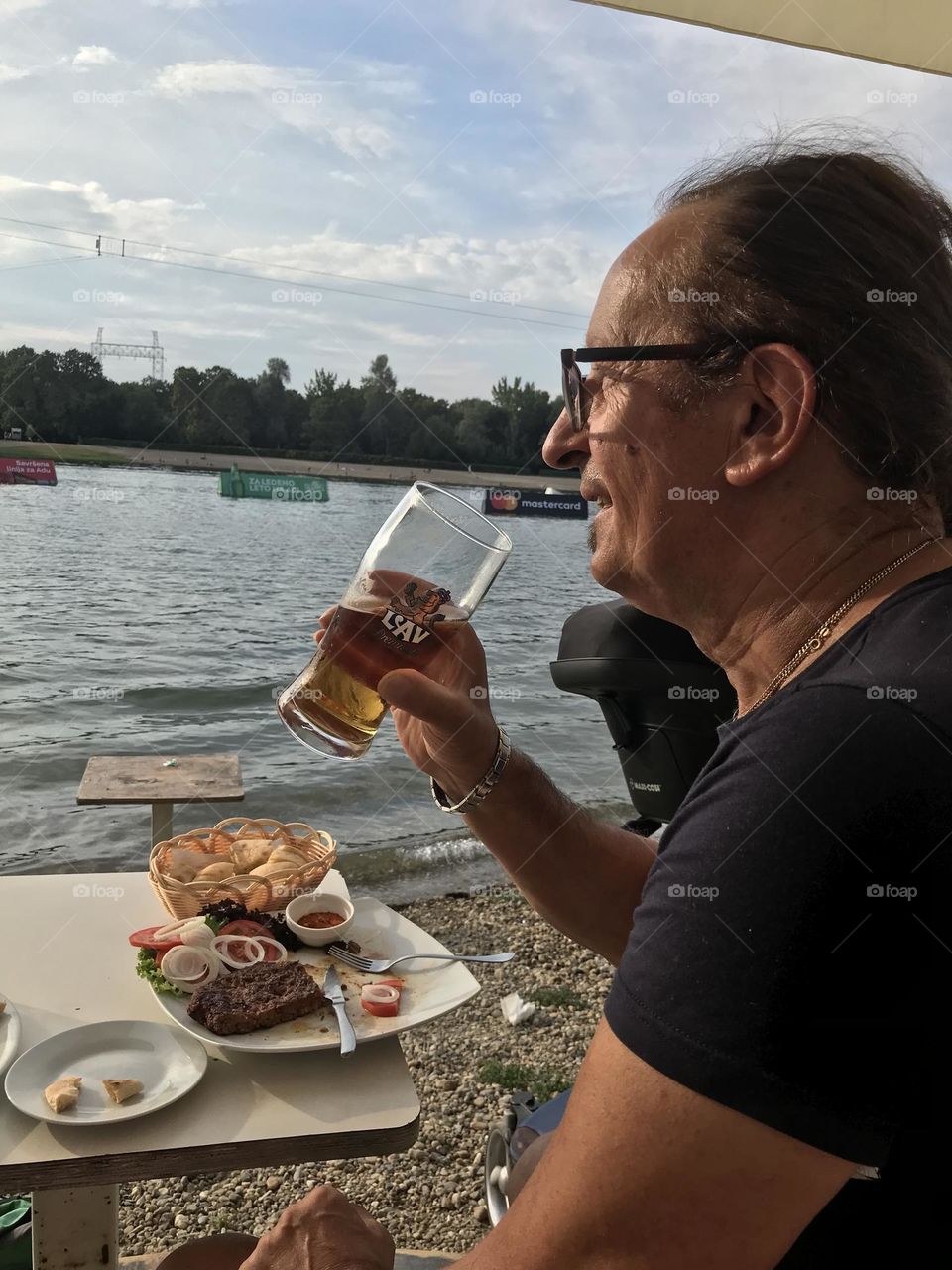 the time of the annual vacation, a man has lunch and drinks beer on the seashore