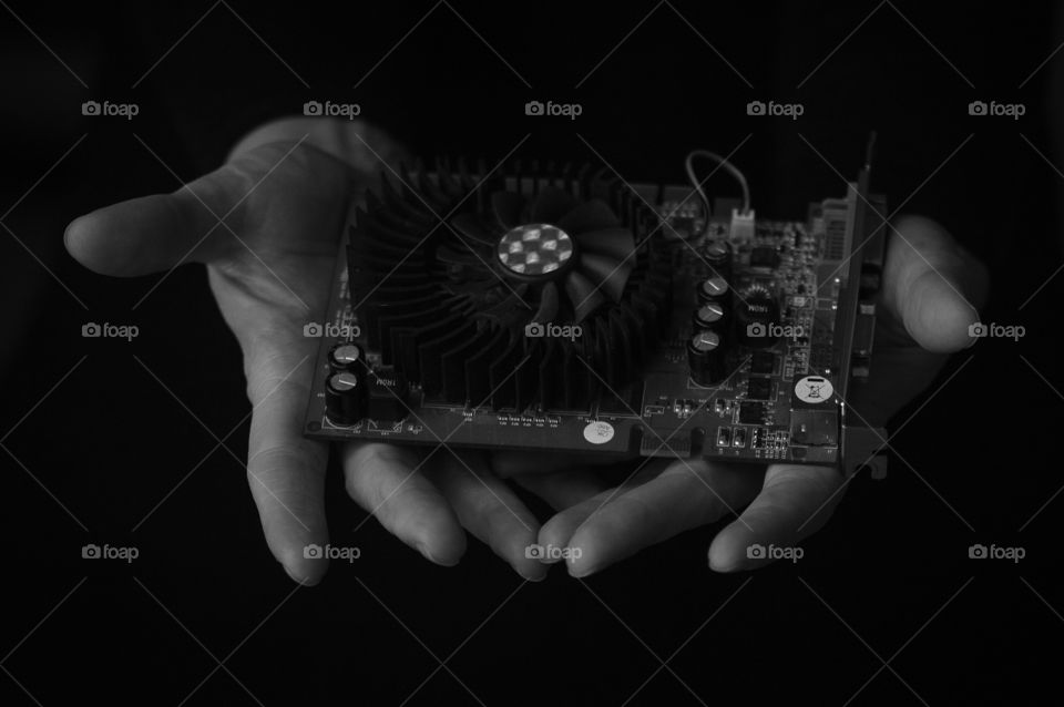 High tech video card held in human hands black and white