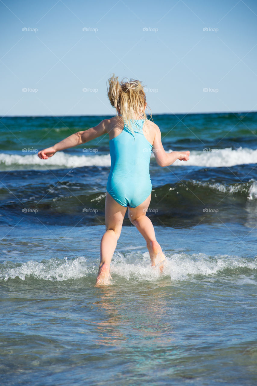 Two young sisters age five and three playing on the beach in Höllviken in Sweden.