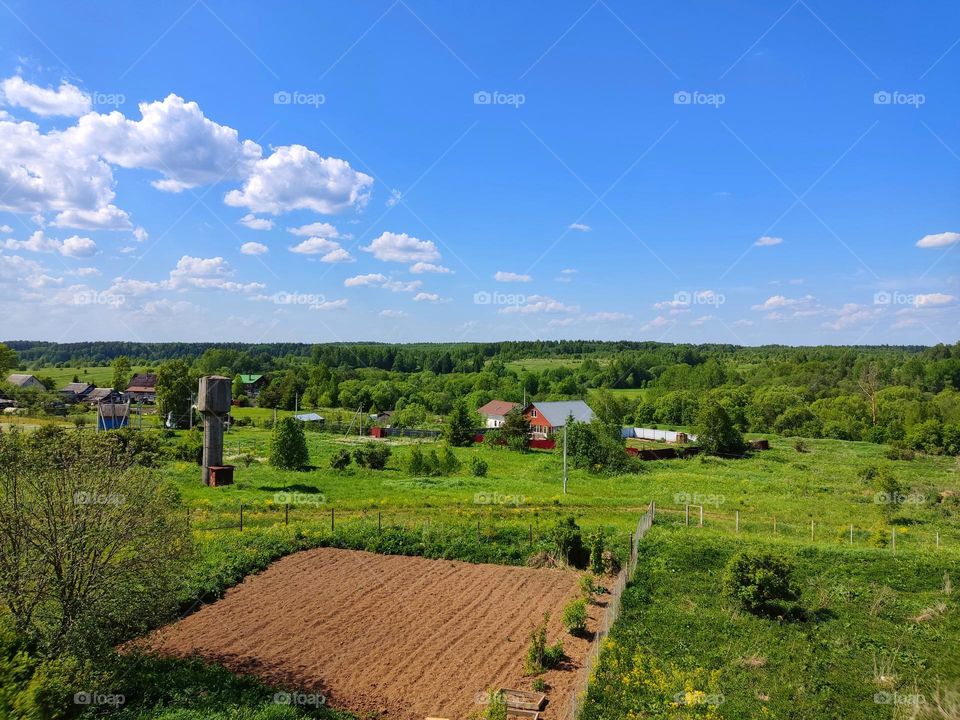 rural landscape with a plowed plot. blue spring sky and forest to the horizon. shooting from above.