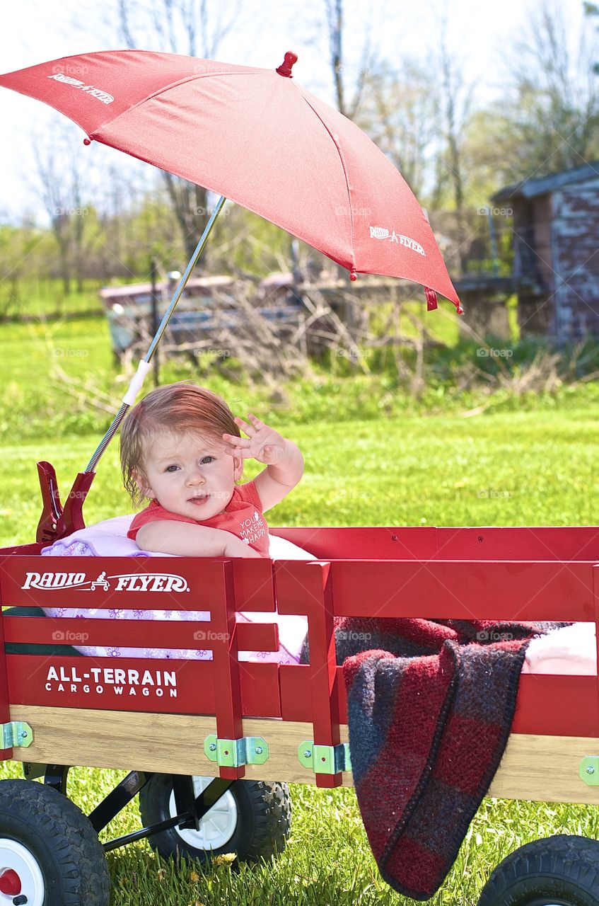 Little red wagon with the umbrella. Baby in the umbrella wagon