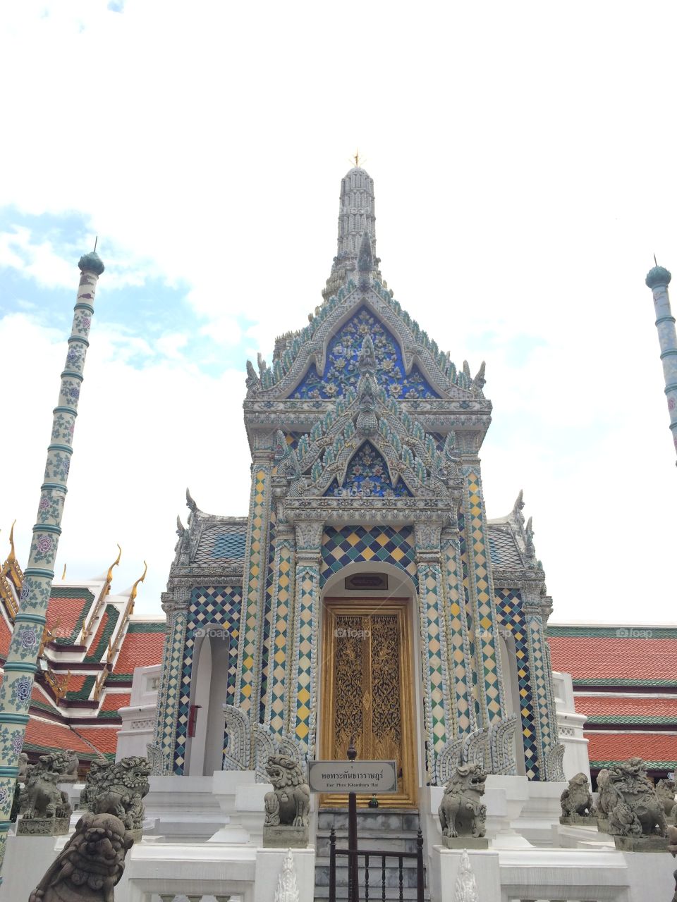 Bangkok, Thailand: Grand Palace temple with mosaic tiles, yellow and blue tiles, wooden doors, and gold Buddha