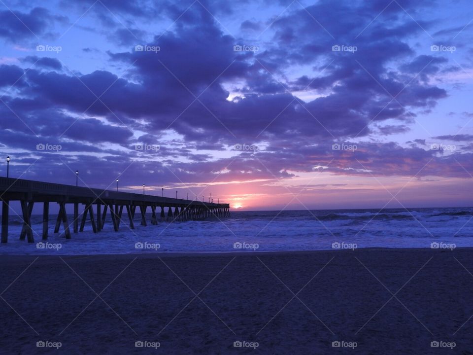 Sunrise over the ocean at Wrightsville Beach with the silhouette of Johnnie Mercer's pier