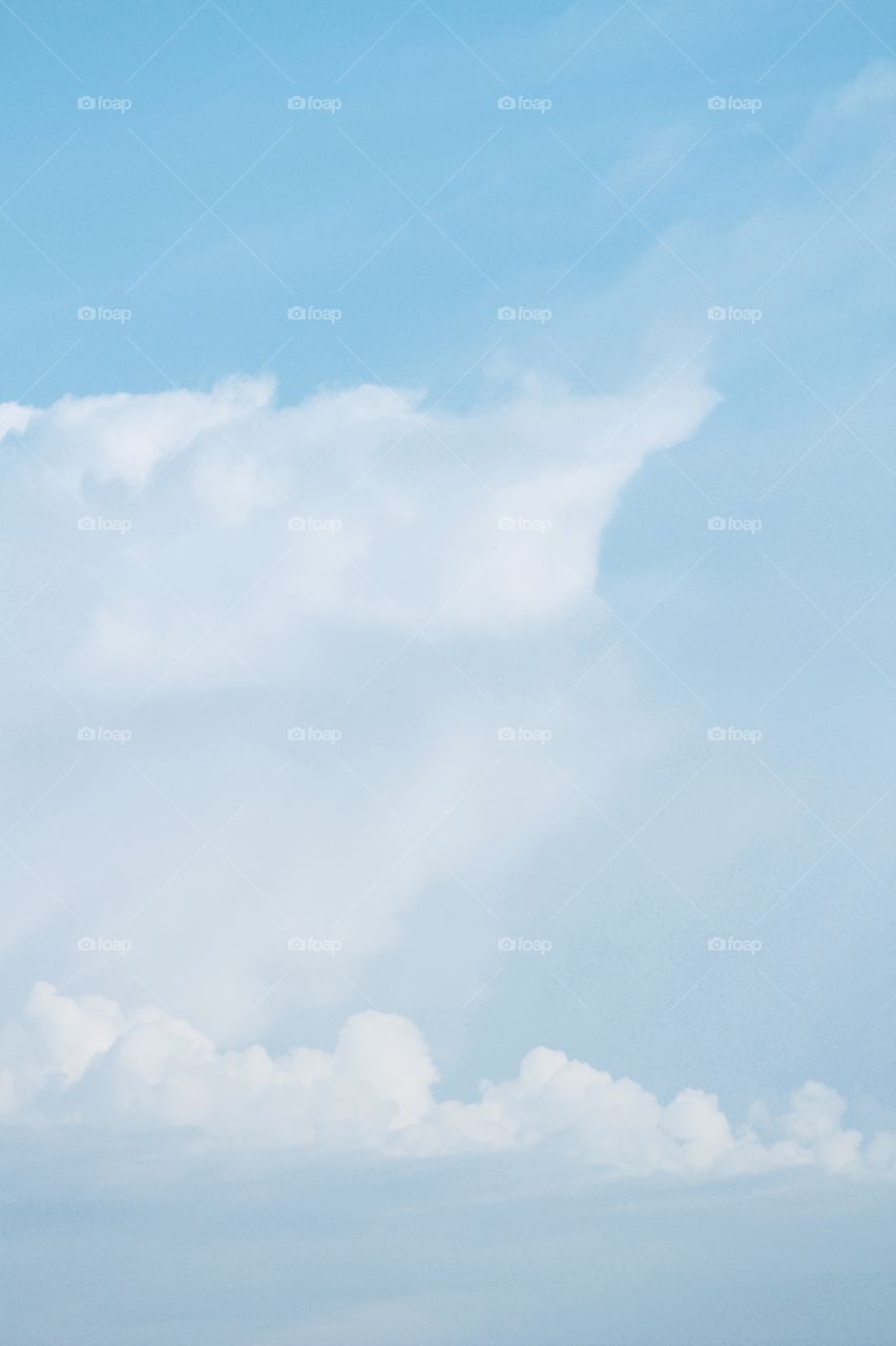 Towering white clouds against a pale blue sky