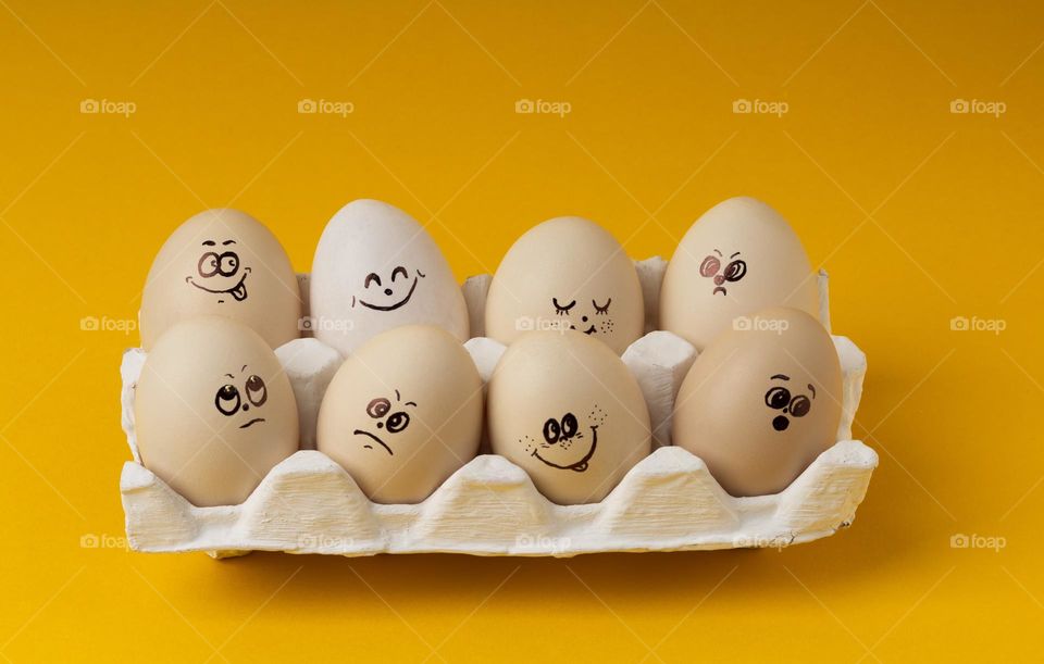 Chicken Eggs With Smileys For Easter Painting on yellow background .