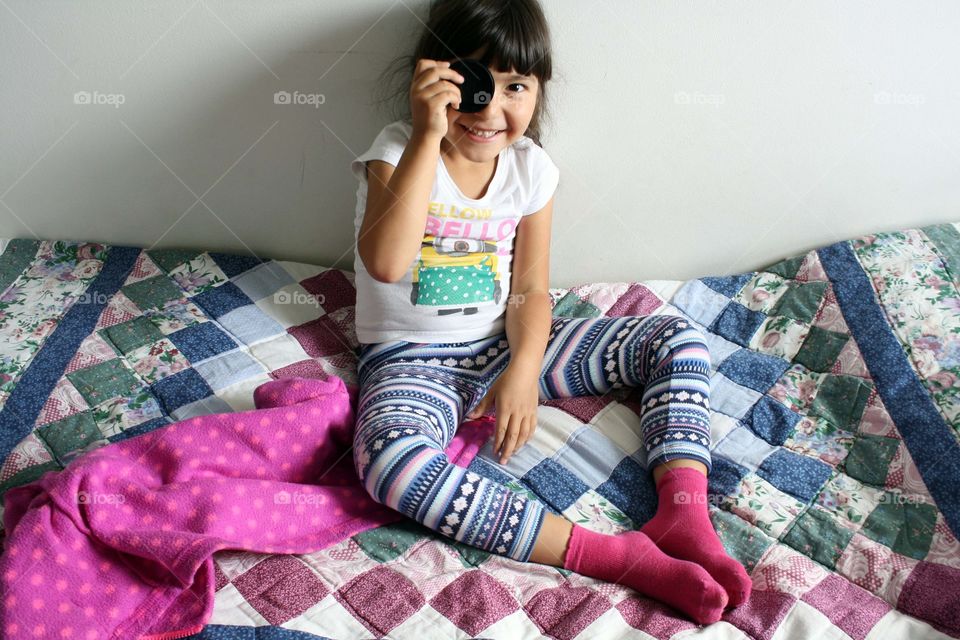 Young girl is playing on a patchwork blanket