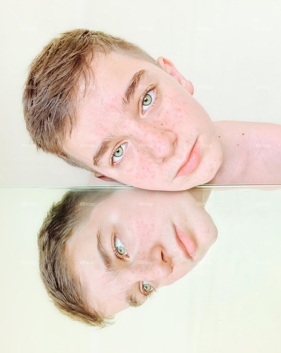 Close-up portrait of boy reflected on mirror 