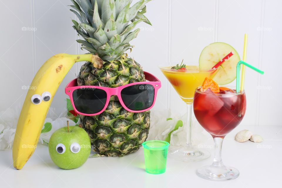 Fruit with funny eyes next to fruity drinks