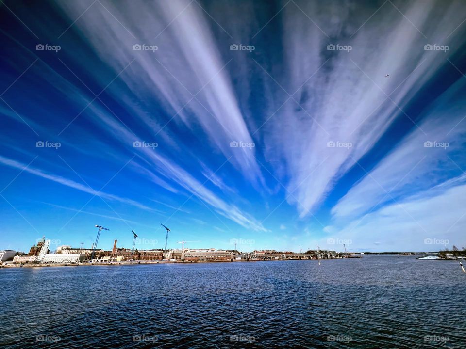 Beautiful bright view to the city coastline of the Baltic Sea and funny shaped white clouds on the deep blue sky 