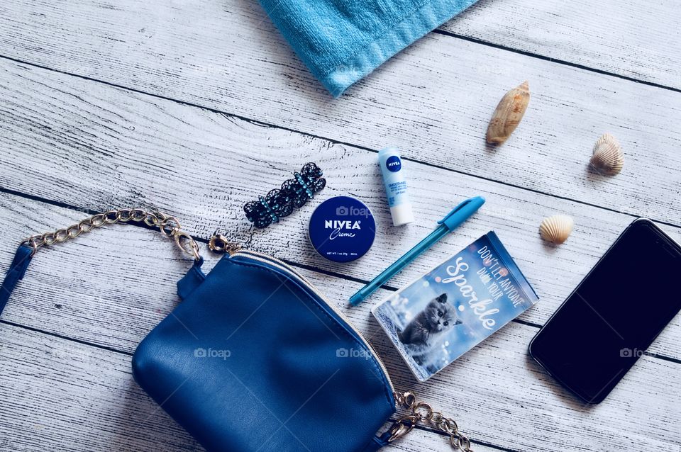 Nivea summer bag flat lay on a white rustic wooden background with blue towel purse lip moisturizer and original tin
