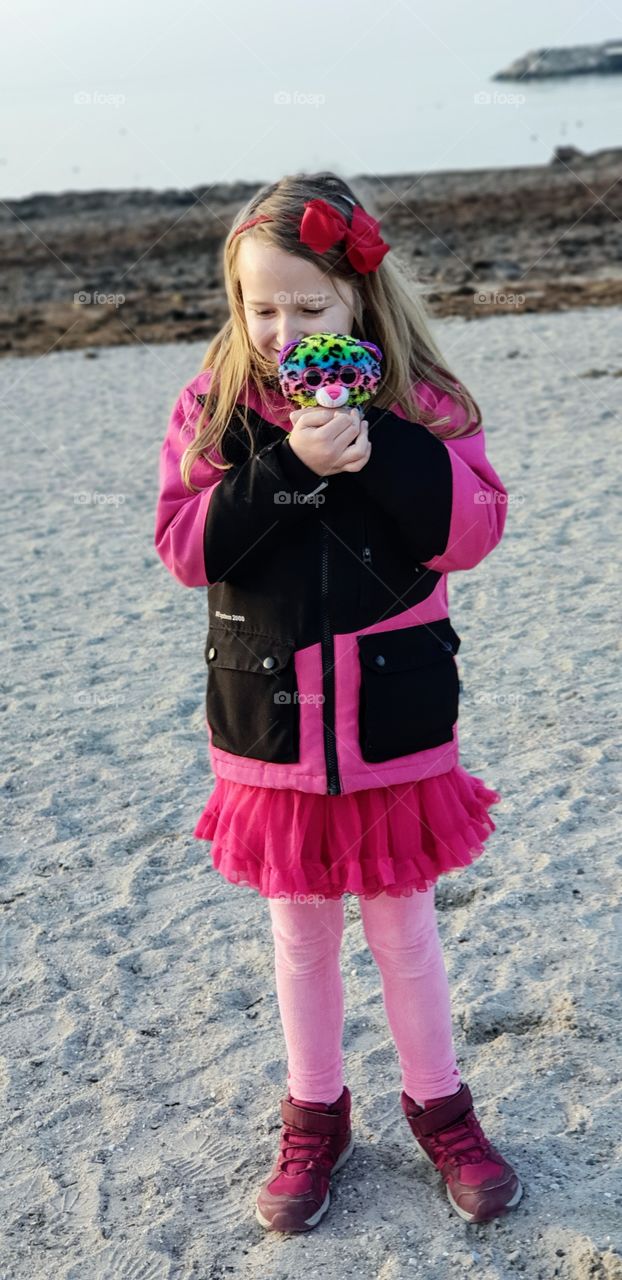 Girl at beach with a teddy bear in winter