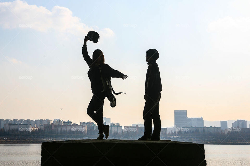 Silhouette of girl dancing with boy during sunset