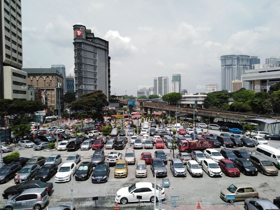 A view from rooftop that shows carpark and a busy city.