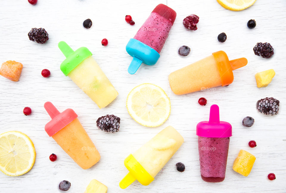 Colourful Fruit  Ice lolly smoothies on a flat lay surrounded by fresh fruit ingredients 