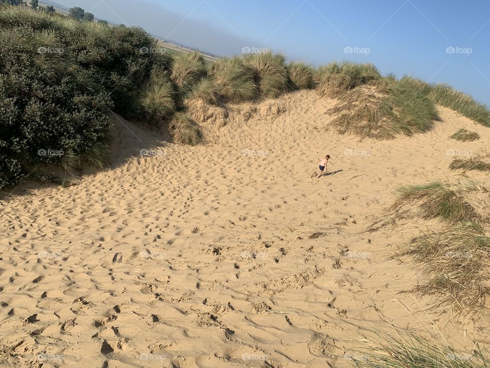 Child playing in the dunes at Camber sands 