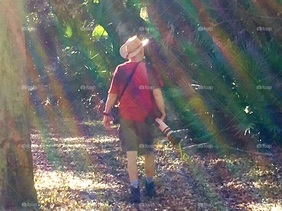 Hiking photographer bathed in rainbow sunbeams.