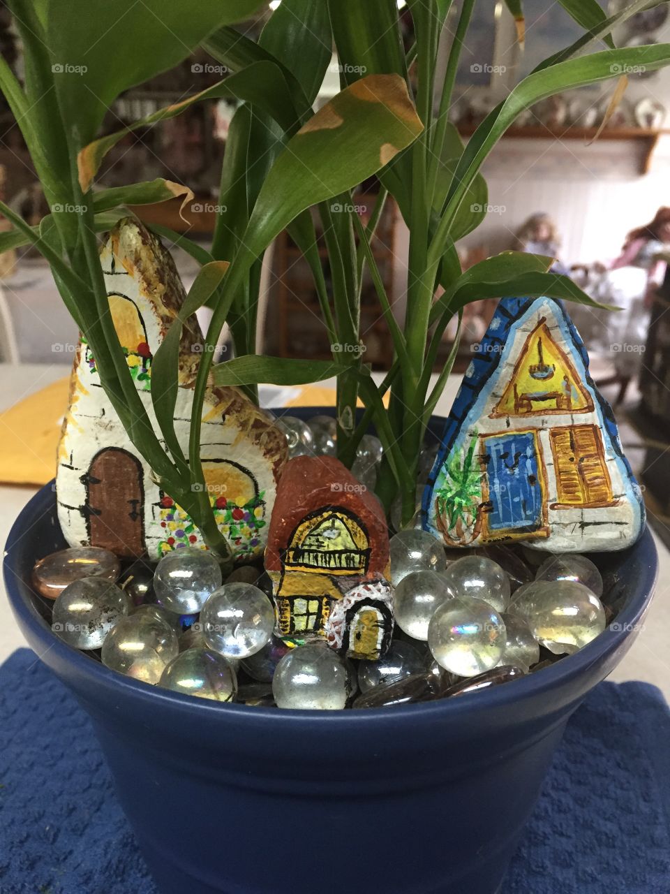 Fairy cottages. Painted stone cottages sharing a plants pot. 