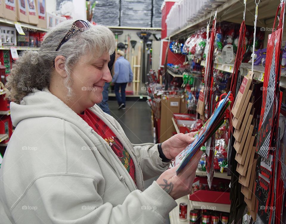 A woman smiles at the designs on various Christmas gift bags while shopping during the holidays. 