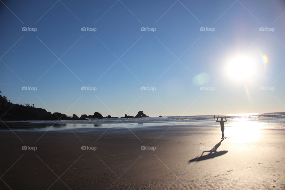 Surfer walking away from sunset 