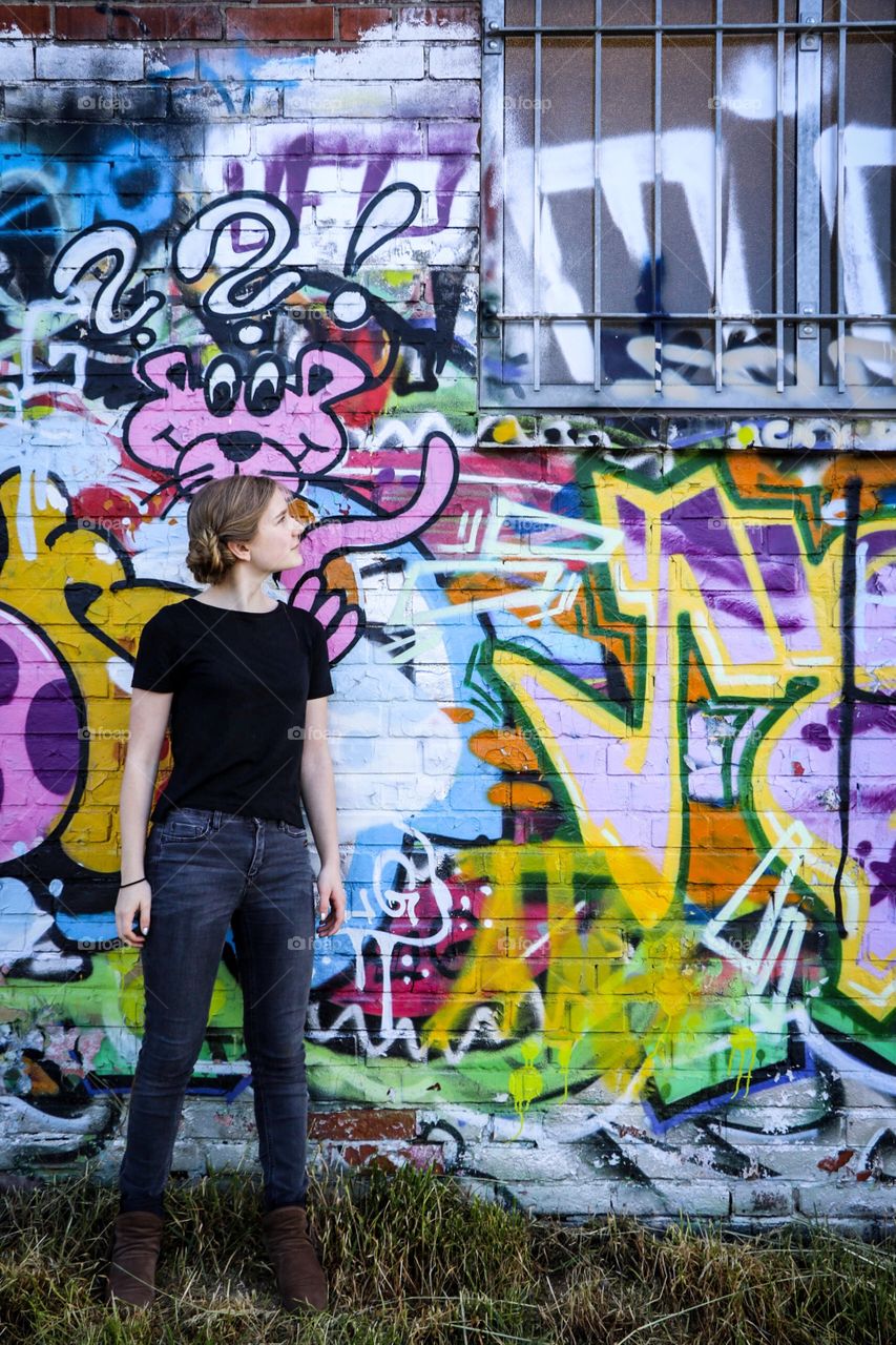Stylish woman looking at graffiti wall