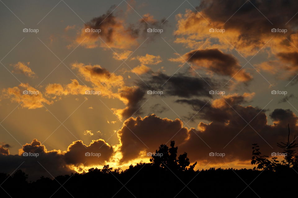 The rays of the setting sun make their way through the clouds