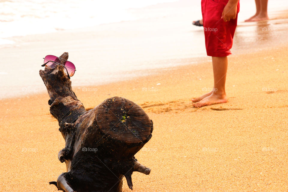 Sunglasses in beach shore, foot prints in Beach