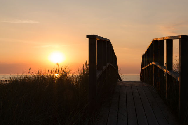 Wooden boardwalk leading to the ocean, beautiful warm colors at sunset in golden hour 