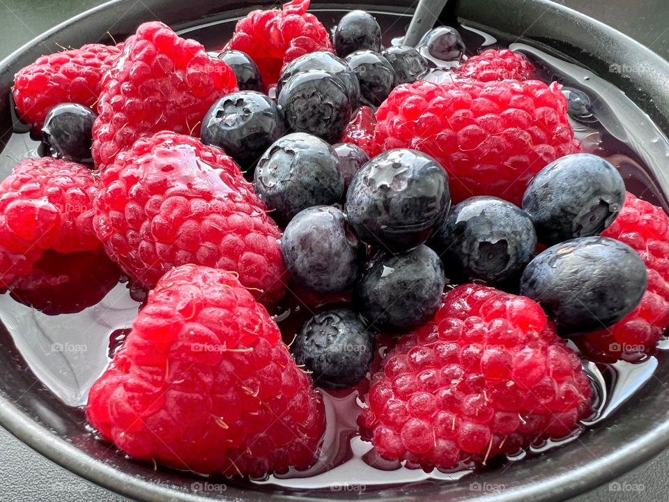 Close up of bright fresh berries blueberries and raspberries in juice soap 