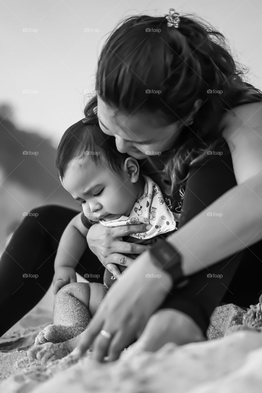 mother and child having fun with sand on the beach