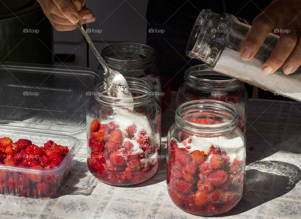 Preparation of raspberries compote, jars full of raspberries and sugar