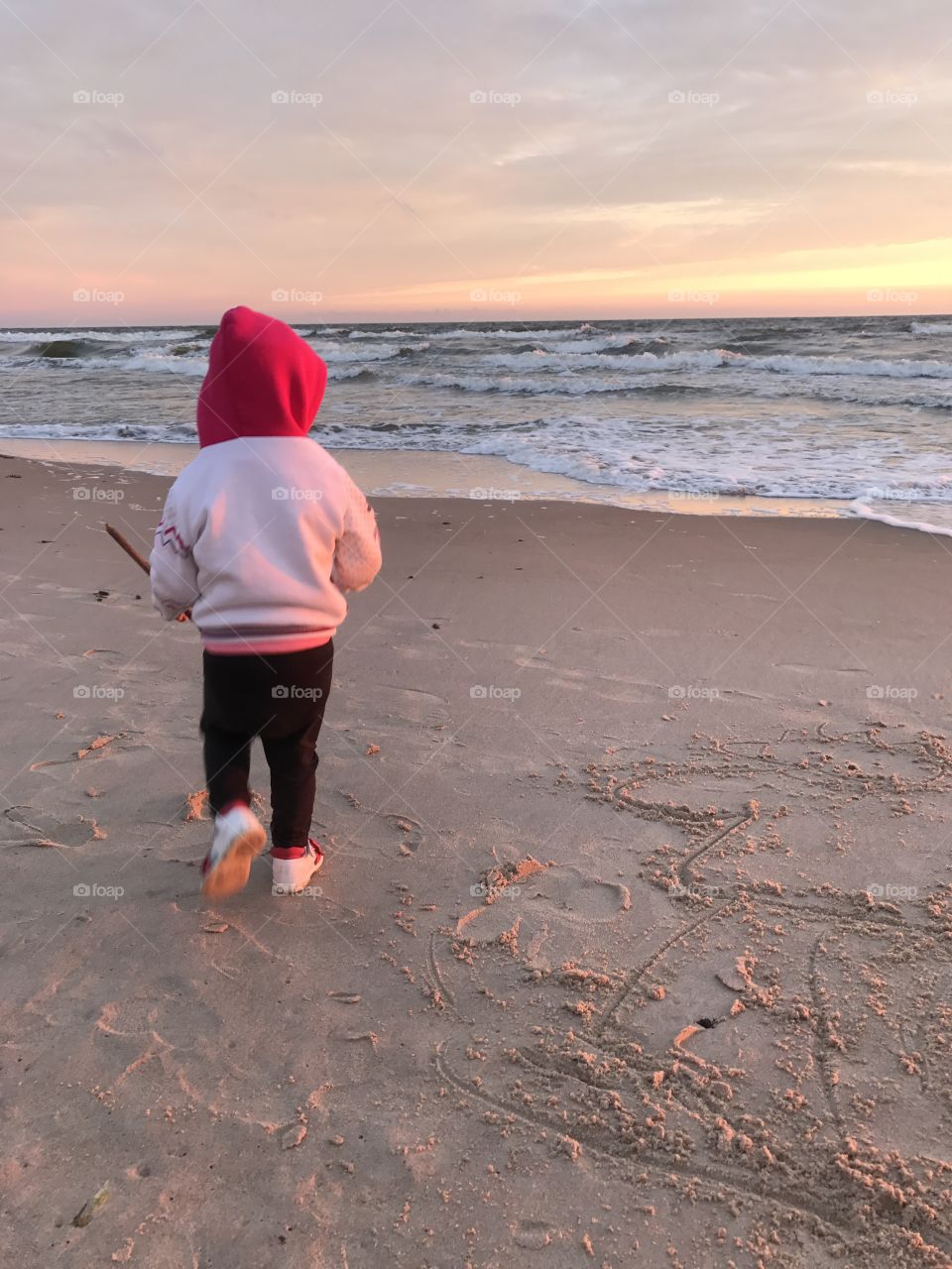 Baby draw on the sand on sunset 