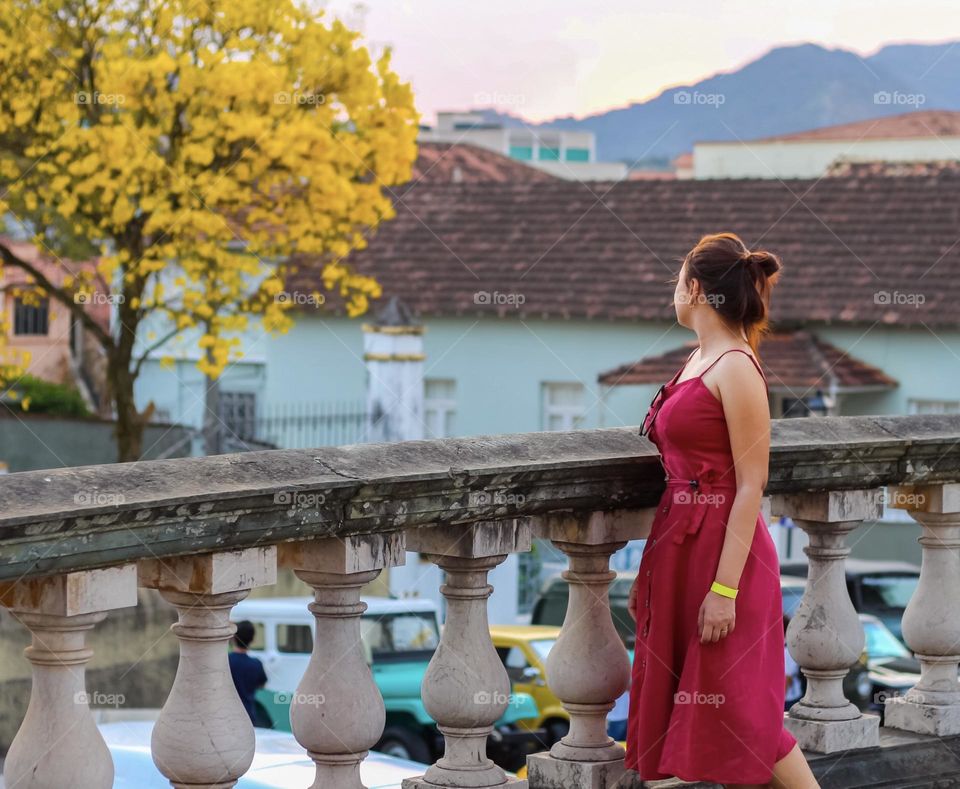 Woman in red dress admiring a beautiful tree with yellow leaves