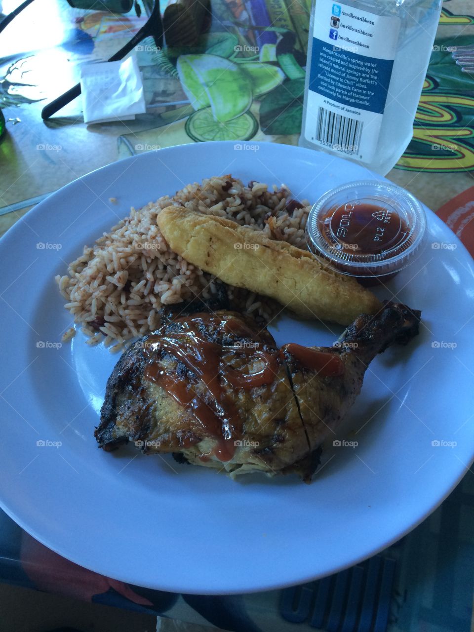 Authentic jerk chicken with rice and beans and festivals. Jamaican sunset in the back causing the blue over cast as it starts to get dark on the beach. 