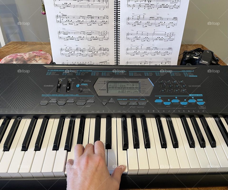 This middle aged lady is Playing a romantic song, on the keyboard with her Kodak camera in top right hand corner