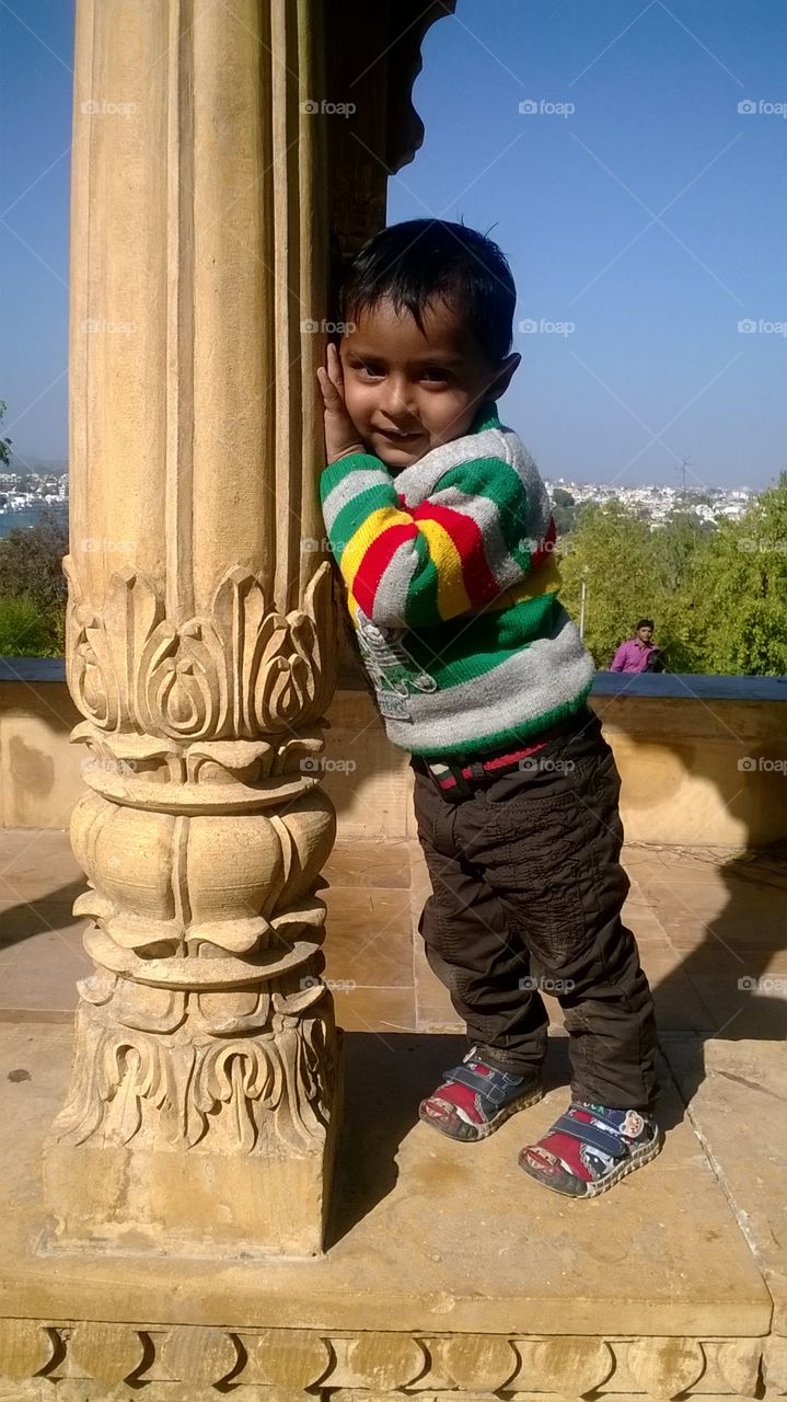 kid standing besides a Piller in a beautiful pose